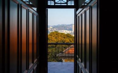 Gulangyu (Kulangsu) Xiamen Hotel Gallery-Open Doors Open wooden doors in a Gulangyu (Kulangsu) Xiamen hotel, offering a view of the cityscape and lush greenery.